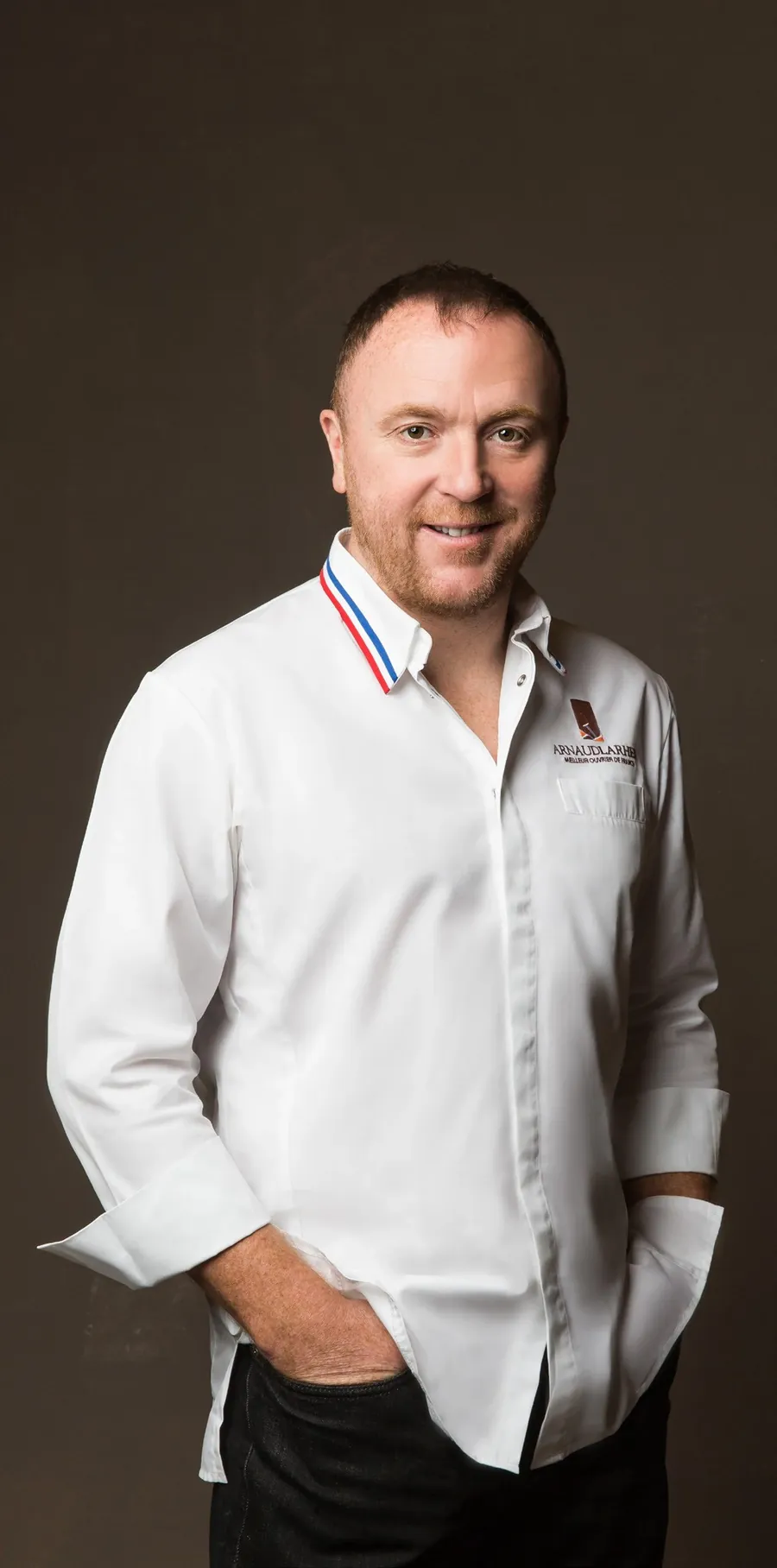 Arnaud Larher, Meilleur Ouvrier de France Pâtissier, in a white chef’s jacket with the tricolour collar, photo by Fauchon