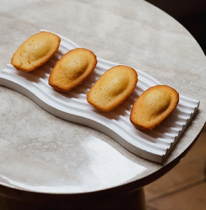 Four madeleines on a white ridged dish, photo by Fauchon